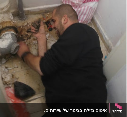 אדם עובד על צינור עם כלי עבודה